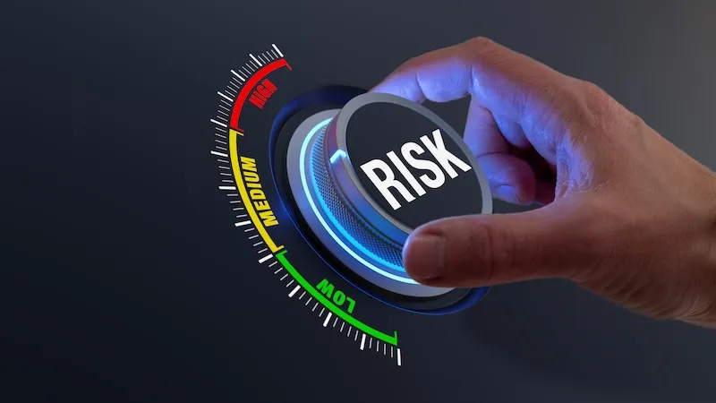 Hand turning a dial labeled “Risk” from low through medium toward high